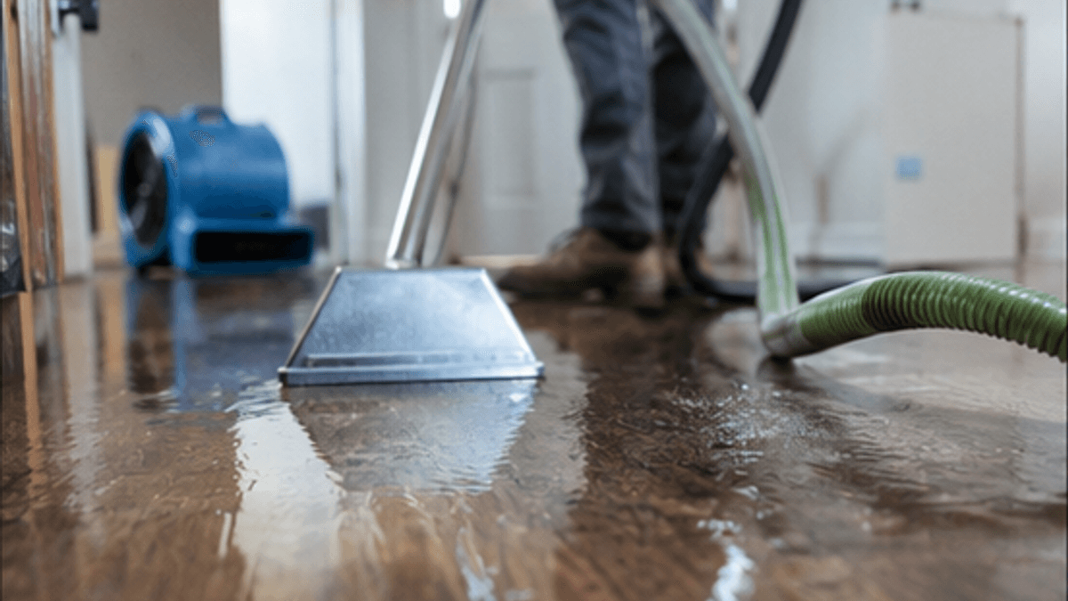 Technician extracting standing water from a flooded home interior