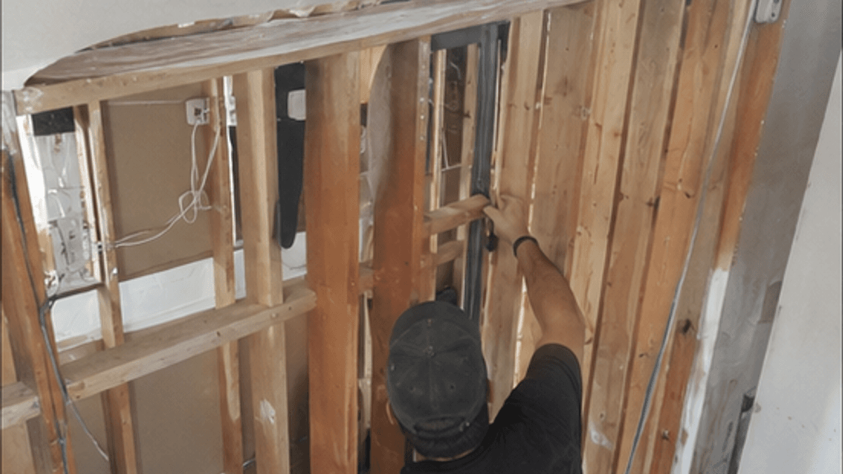 Technician repairing exposed wall framing after water damage